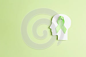World mental health day concept. Green awareness ribbon with brain symbol on a green background
