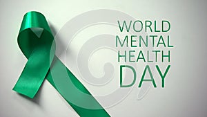 World mental health day inscription, green ribbon on table, awareness campaign