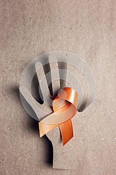 World Multiple Sclerosis Day. Orange awareness ribbon and hand silhouette on a brown background