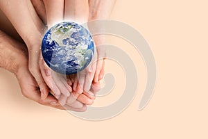 World in our hands. Top view of parents and kid holding digital model of Earth on beige background, space for text