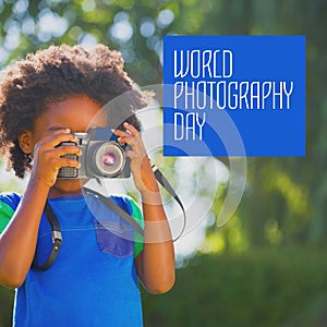 World photography day text in white on blue over african american girl using camera in sunny garden