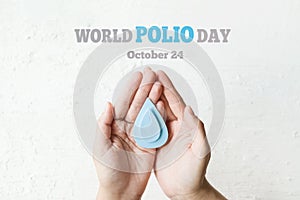 World Polio day. October 24. Blue drop in hands of an adult is symbol of polio vaccine. Poliomyelitis is disabling and