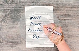 World Press Freedom Day is standing on a paper, hand with pen is chained, free speech, cancel culture, journalist writing