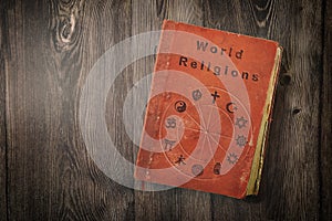 World religions book with symbols on wooden table top view