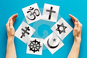 World religions concept. Hands hugs Christianity, Catholicism, Buddhism, Judaism, Islam symbols on blue background top photo