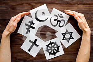 World religions concept. Hands hugs Christianity, Catholicism, Buddhism, Judaism, Islam symbols on wooden background top