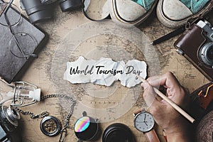 World Tourism Day Hand Writing. Travel Concept Background. Overhead View of Traveler`s Accessories on Old Vintage Map