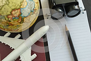 World travel concept with toy airplane, pencil binoculars, passport, note and globe on black background