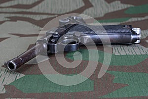 World War II period german army handgun with german award Iron Cross 1914 on camouflaged