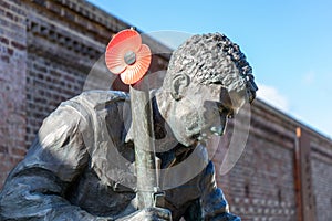 A world war two soldier statue with a red poppy attached to his rifle