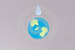 World Water Day. Carved out of felt is the symbol of the planet Earth and a drop of water. Gray background. Copy space.