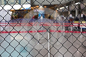 Worldwide coronavirus pandemic. Empty airport, check-in area  behind steel mesh wire fence. Flight ban and closed borders