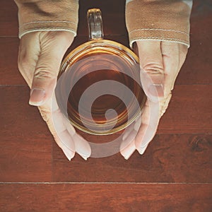 Worm teaÃ¢â¬â¹ in glass tea cup on woman's hand