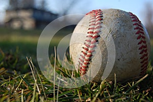 A worn baseball in the grass