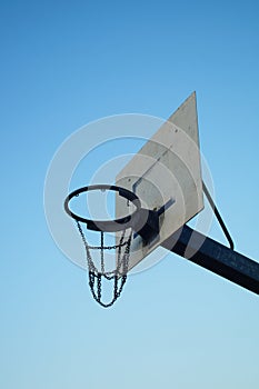 A worn basketball hoop in a public recreational area.