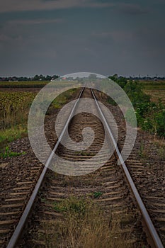 Worn and bent railorad tracks between the fields in Romania. Poor shape of railway tracks through the fields