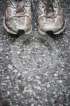 Worn, dirty, smelly and old running shoes on a tarmac road