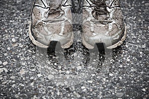 Worn, dirty, smelly and old running shoes on a tarmac road