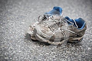 Worn, dirty, smelly and old running shoes on a tarmac road photo