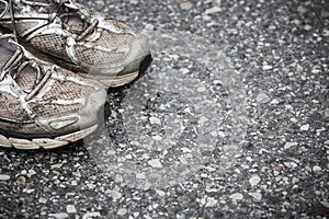 Worn, dirty, smelly and old running shoes on a tarmac road photo