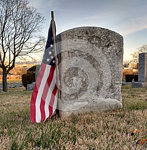 Worn Gravestone of a Military Veteran Honored with an American Flag