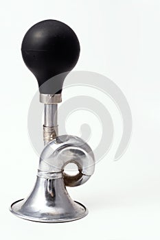 A worn iron horn or klaxon from a vintage car or bicycle lies horizontally. Isolated on a light background with a shadow.