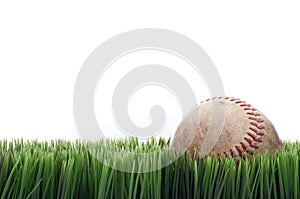 A worn leather baseball in grass