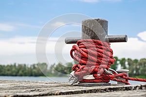 Worn old rusty mooring bollard with heavy ropes on the deck of a ship, closeup.