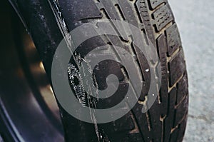 Worn out car tire with hole and steel cable.