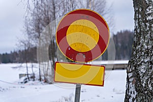 Worn out finnish prohibited entry traffic sign in winter with blank yellow sign
