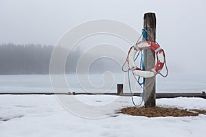 Worn-out lifesaver on post at foggy lake scape
