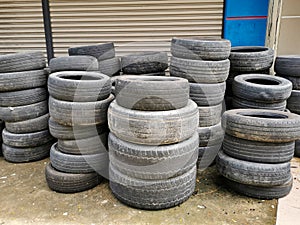 Worn out and used automobil tires stacked on workshop concrete floor. photo