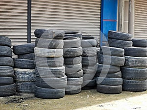 Worn out and used automobil tires stacked on workshop concrete floor. photo