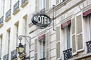 The worn period sign of an hotel and a vintage street light fixed to an old building in Paris