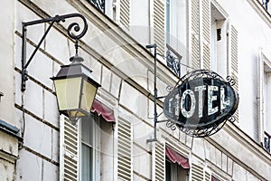 The worn period sign of an hotel and a vintage street light fixed to an old building in Paris