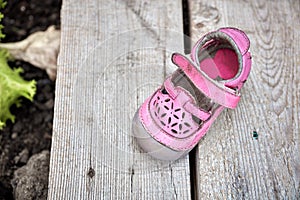 Worn pink children shoe on wooden plank background