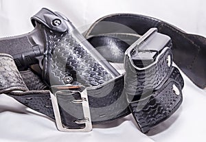 A worn police duty belt with a black pistol and two pistol magazine case wrapped up photo