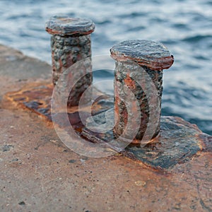 Worn rusty bollards on old concrete pier