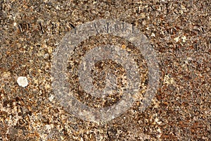 Worn rusty metal surface with partly readable Latin letters