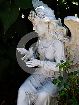 Statue Of Female Angel Holding Bird In Garden