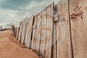 Worn wooden fence on sandy beach