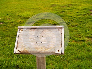 Worn wooden sign in grassy field