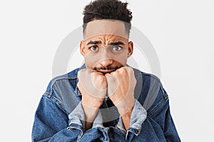 Worried african man in denim jacket covering mouth with fists