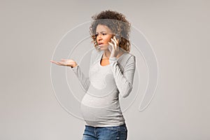 Worried afro pregnant woman talking on phone