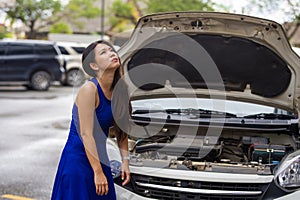 Worried Asian Japanese woman in stress stranded on street roadside with car engine failure having mechanic problem needing repair