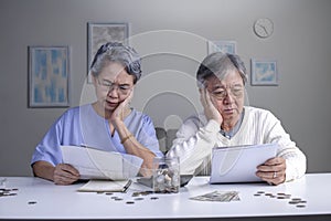 Worried Asian senior family couple reading financial documents or notification letter with bad news from bank while paying bills
