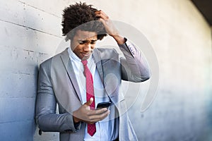 Worried Black Businessman using his smartphone outdoors. photo