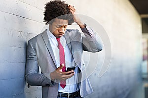 Worried Black Businessman using his smartphone outdoors. photo