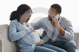 Worried black man calling doctor while wife having laibor pains