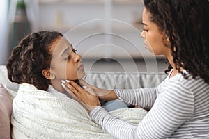 Worried black mother rubbing her sick daughter glands